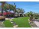 Lush backyard featuring manicured lawn, mature trees, colorful flowers, and inviting stepping stone pathway at 26647 N 43Rd N St, Cave Creek, AZ 85331
