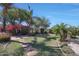 Lush backyard featuring manicured lawn, mature trees, colorful flowers, and inviting stepping stone pathway at 26647 N 43Rd N St, Cave Creek, AZ 85331