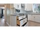 Bright kitchen featuring white cabinetry, granite countertops, stylish backsplash, and stainless steel appliances at 26647 N 43Rd N St, Cave Creek, AZ 85331