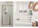 Bright bathroom featuring a soaking tub, framed art, a window and a glass enclosed shower at 2747 S 85Th Way, Mesa, AZ 85209