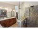 Modern bathroom with double sinks, wood cabinets and granite countertops with a shower featuring decorative tile at 4002 N San Gabriel Cir, Mesa, AZ 85215