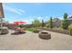 Backyard with paved patio, artificial turf, fire pit, seating, landscaping, and red umbrellas at 41215 W Almira Dr, Maricopa, AZ 85138
