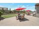 Wide shot of the backyard patio with pavers, two red umbrellas, outdoor furniture, and artificial grass at 41215 W Almira Dr, Maricopa, AZ 85138