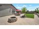The backyard features pavers, artificial grass, a fire pit, two red umbrellas, and outdoor furniture at 41215 W Almira Dr, Maricopa, AZ 85138