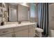 Clean bathroom with a white vanity, large mirror, and a shower with a gray curtain at 41215 W Almira Dr, Maricopa, AZ 85138