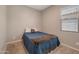 Comfortable bedroom with neutral walls and cozy carpet, illuminated by natural light from a window at 41215 W Almira Dr, Maricopa, AZ 85138