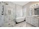 Modern bathroom featuring a soaking tub, frameless shower, marble tile, and white cabinets at 422 E Kaibab Pl, Chandler, AZ 85249