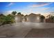 Exterior view of a three-car garage with wide driveway under a colorful sky at dusk at 422 E Kaibab Pl, Chandler, AZ 85249