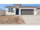 Charming single-Gathering home featuring a two-car garage, desert landscaping, and a modern blue front door at 5566 S 254Th Gln, Buckeye, AZ 85326
