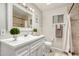 Stylish bathroom with a white vanity, decorative mirror, and a shower with neutral tile at 5649 W Holly St, Phoenix, AZ 85035
