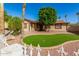 A single-story home with a charming front yard, lush lawn, and mature trees at 5649 W Holly St, Phoenix, AZ 85035