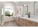 Bathroom with large arched window, wood cabinets, quartz counters, and glass shower at 6439 E Redmont Dr, Mesa, AZ 85215