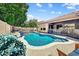 Backyard pool with lush greenery, waterfall feature, and comfortable seating area at 776 W Carob Way, Chandler, AZ 85248