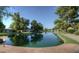 Picturesque lake view surrounded by mature trees and well-maintained lawns. Sign reads, 