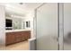 Bathroom featuring double sinks, a vanity with storage, and a step-in shower at 17562 W Gelding Dr, Surprise, AZ 85388