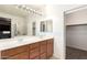 Bathroom featuring double sinks, a large mirror, wood cabinets, and walk-in closet at 17562 W Gelding Dr, Surprise, AZ 85388