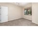 Bedroom features neutral colored walls, carpet flooring, and a large window for natural light at 17562 W Gelding Dr, Surprise, AZ 85388
