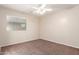 This bedroom features neutral walls, a ceiling fan and a large window at 17562 W Gelding Dr, Surprise, AZ 85388