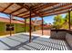 Spacious pergola with concrete flooring overlooking a large backyard with mature trees and gravel at 2109 E Gelding Dr, Phoenix, AZ 85022