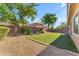 A peaceful backyard featuring a plush lawn, mature trees, and decorative stone ground cover at 2459 E Lindrick Dr, Gilbert, AZ 85298