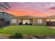 Well-maintained backyard featuring artificial turf, covered patio, and desert landscaping under a vibrant sunset at 2459 E Lindrick Dr, Gilbert, AZ 85298