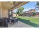 Relaxing covered patio with seating overlooks a green artificial turf lawn and landscaped backyard at 2459 E Lindrick Dr, Gilbert, AZ 85298