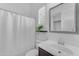 Bathroom features a white shower curtain, mirror, modern vanity, and natural light from the shuttered window at 2459 E Lindrick Dr, Gilbert, AZ 85298