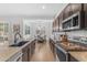 Open-concept kitchen featuring dark wood cabinets, granite countertops, stainless appliances, and hardwood floors at 2459 E Lindrick Dr, Gilbert, AZ 85298
