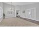 Open-concept living room with modern lighting fixtures, connecting doorway, and tile-to-carpet flooring at 2911 E Leland St, Mesa, AZ 85213