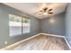 A bright bedroom has light wood floors, a ceiling fan, and large window at 29688 W Indianola Ave, Buckeye, AZ 85396