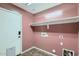 A simple laundry room with mauve walls, tile floors, a shelf, and hookups at 29688 W Indianola Ave, Buckeye, AZ 85396