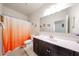 Well-lit bathroom with an orange accented shower curtain, vanity, and large mirror at 30186 W Pinchot Ave, Buckeye, AZ 85396