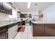 Well-lit kitchen featuring granite counters, stainless steel appliances, and tile floors, alongside dark wood cabinetry at 30186 W Pinchot Ave, Buckeye, AZ 85396