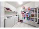 Functional laundry room equipped with a washer, dryer, tiled floors, and ample shelving for storage and organization at 30186 W Pinchot Ave, Buckeye, AZ 85396