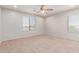 Bright, carpeted bedroom with two windows and a ceiling fan at 31700 N Sunflower Way, San Tan Valley, AZ 85143