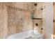 Bathroom with neutral colored travertine walls and a glass enclosed bathtub and shower at 38106 N 2Nd Ln, Phoenix, AZ 85086
