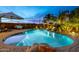 Beautiful backyard pool with rock accents and palm trees, illuminated for evening enjoyment and relaxation at 38106 N 2Nd Ln, Phoenix, AZ 85086