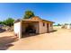 Side view of an outbuilding with an open bay, a pedestrian door and open dirt lot at 4145 W Banff Ln, Phoenix, AZ 85053