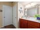 Bathroom with wood vanity, large mirror, white countertops and cabinet storage at 6319 W Mercer Ln, Glendale, AZ 85304