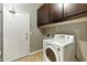 Bright laundry room featuring a white washer, dark cabinets, tile flooring and access to the backyard at 6967 W Irma Ln, Glendale, AZ 85308