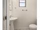 A well lit half bathroom with a pedestal sink, toilet, and small window is on display at 716 S Lewis --, Mesa, AZ 85210