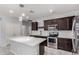 Gourmet kitchen with dark cabinetry, stainless steel appliances, and quartz island with pendant lighting at 7423 S 28Th Pl, Phoenix, AZ 85042