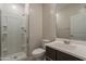 Bathroom with white tile shower, toilet, vanity with sink, and large mirror with lighting at 9155 W Minnezona Ave, Phoenix, AZ 85037