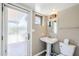 Bathroom with pedestal sink, modern fixtures, white toilet, and a glass door leading to the outdoors at 9421 E Calle De Valle Dr, Scottsdale, AZ 85255