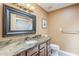 Bathroom with granite countertop, framed mirror, vanity with wooden cabinets, toilet, and shower in the background at 9421 E Calle De Valle Dr, Scottsdale, AZ 85255