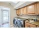 Laundry room featuring granite countertop, sink, wooden cabinets, skylight, and modern washer and dryer machines at 9421 E Calle De Valle Dr, Scottsdale, AZ 85255