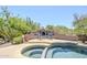 Backyard oasis featuring a swimming pool, spa, outdoor fireplace, mature trees, and desert landscaping under a sunny sky at 9421 E Calle De Valle Dr, Scottsdale, AZ 85255