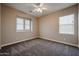 A bedroom with neutral walls, carpet, baseboards, a ceiling fan, and two large windows at 10036 E Naranja Ave, Mesa, AZ 85209