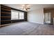 A spacious carpeted bedroom with a ceiling fan, two windows, and built-in shelves at 10036 E Naranja Ave, Mesa, AZ 85209