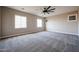 Spacious room featuring neutral paint, carpet, a modern ceiling fan and natural light from two windows at 10036 E Naranja Ave, Mesa, AZ 85209